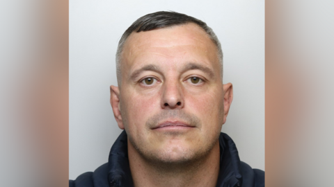 Gareth Whitehouse's mugshot. He is wearing a dark jacket and has short, dark and greying hair.