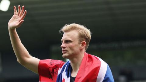 Sondre Langas waving while draped in a Norwegian flag