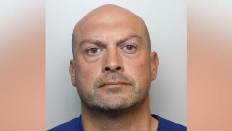 Police image of Edward Blackmore, who has a bald head and is in a blue top