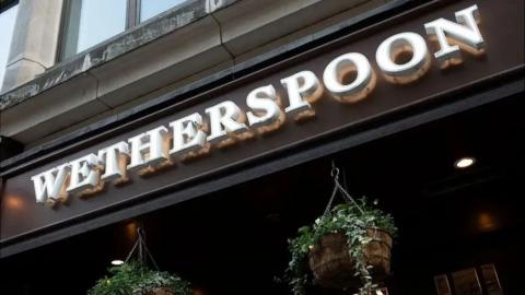 A pub sign which reads "Wetherspoon". There's hanging baskets below.