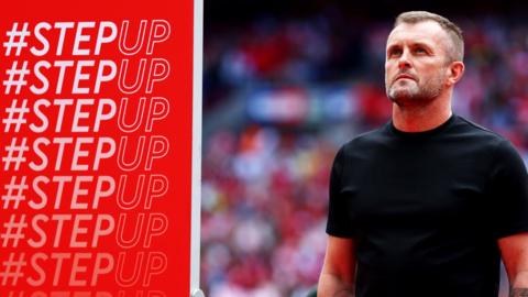 Nathan Jones stands next to a Step Up banner