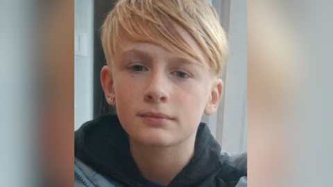 A young boy with blonde hair, he has an earing in his ear.