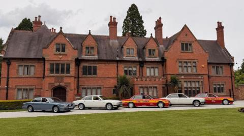 Five Jaguar XJ40s, including two in Fire Service livery, are parked outside Wappenbury Hall, a medieval manor house extended in the Victorian era, as part of Coventry Motofest.