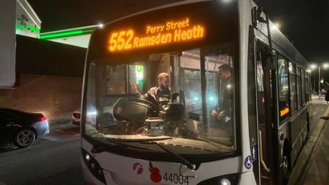 The 552 Billericay to Ramsden Heath service operated by First at a bus stop in the dark with its lights on