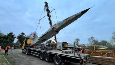 F5 replica jet hoisted on a trailer and crane