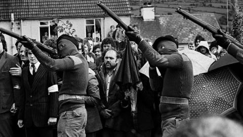 Masked IRA members fire a volley of shots at the funeral of hunger striker Raymond McCreesh in 1981