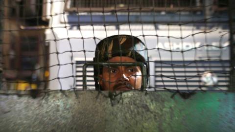 An Indian paramilitary soldier keeps watch from behind a fence