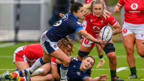 Caity Mattison of Scotland juggles the ball as she is tracked by Alex Callender of Wales