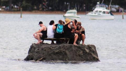 New Year revellers enjoy a drink on a special sand island they constructed earlier in the Tairua estuary on the Coromandel peninsula