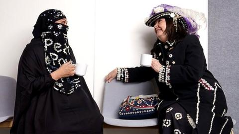 Two women wearing modern versions of the traditional Pearly Queen outfits
