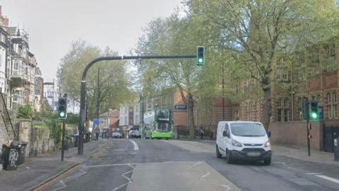 Google Maps street view of Cheltenham Road in Bristol. There are traffic lights and buildings either side of the road. Vehicles can be seen driving along.