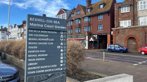 Bexhill's seafront area which will see increases to on street parking. Pictured is a sign which shows different attractions in the town such as the De La Warr Pavilion. Behind it is the seafront road with shops behind