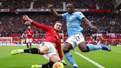 Manchester United defender Diogo Dalot slides in on Manchester City's Jeremy Doku at Old Trafford 