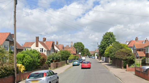 A general view of Church Road in Felixstowe. Houses line both sides of the road while cars are parked up on the left hand side. A red car can be seen driving ahead.