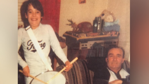 Boy playing drums as his father looks on in photo from the 1980s