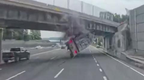 A tractor trailer is flipped over after hitting the overpass.