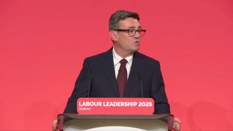 Andy Burnham in a suit giving a speech