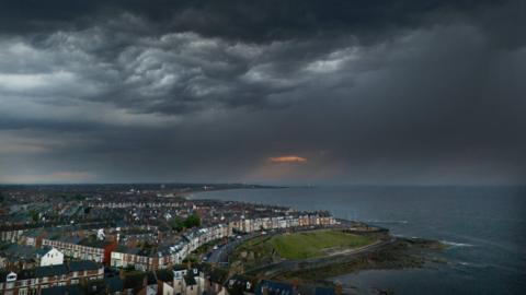 A landscape image of  Whitley Bay in North Tyneside along the coastline. Dark clouds have gathered across the sky.