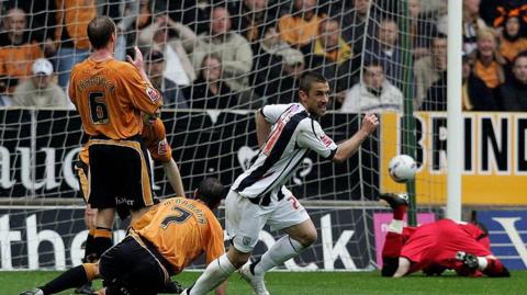 Kevin Phillips of West Bromwich Albion celebrates after scoring the opening goal during the Coca Cola Championship play-off semi final first leg match between Wolverhampton Wanderers and West Bromwich Albion at Molineux on May 13, 2007 in Wolverhampton, England. He is wearing a white and navy striped West Brom shirt and players in orange and black Wolves shirts are trying to stop him from scoring. Wolves keeper, wearing red, is on the floor after failing to save the goal. 
