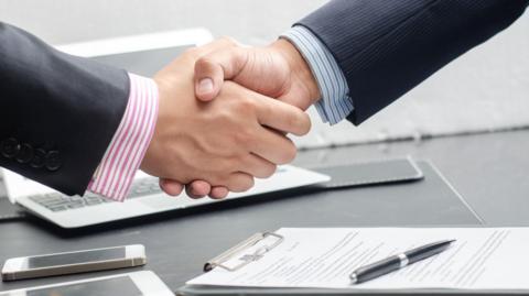 Two people shaking hands after signing a contract