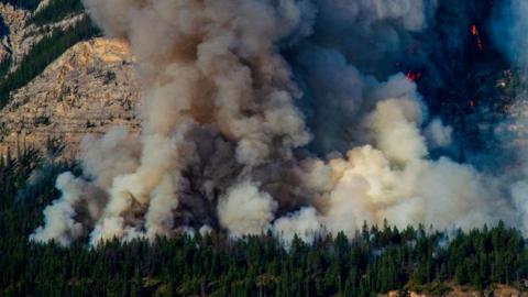 A plume of smoke rises as the Jasper Complex Wildfire continues to burn in Jasper National Park, Alberta, Canada, on 14 August 2024