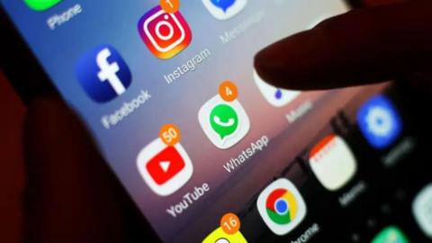 A generic image of a phone and someone about click on WhatsApp.