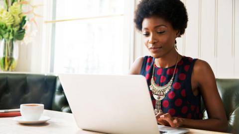 A woman using a laptop while sitting at a table