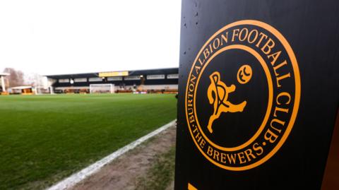 General view of the Pirelli Stadium with a Burton Albion logo in the foreground 