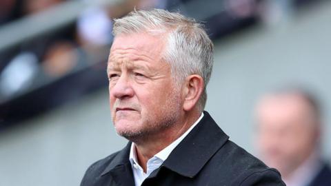 Unshaven Sheffield United manager Chris Wilder looking forward in open neck shirt and rain jacket