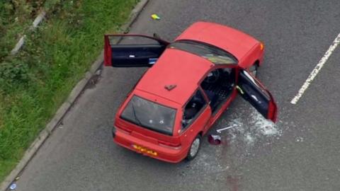 Aerial shot of red car showing bullet holes