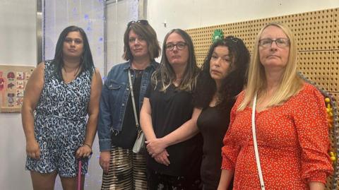 Five mothers standing in a play centre looking a the camera