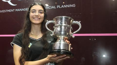 Amino Orfi holding her trophy and smiling
