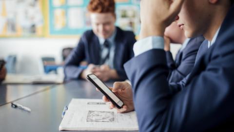 Pupils using their mobile phones in a classroom