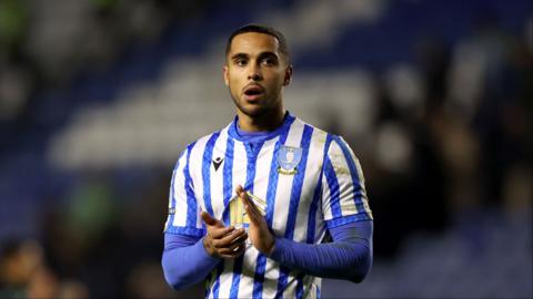 Defender Max Lowe wearing a blue and white striped Sheffield Wednesday shirt claps with a disappointed look on his face