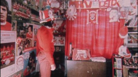 A Manchester United fan dressed in red with a large collection of memorabilia.