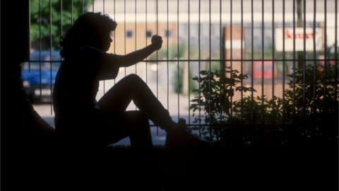 Silhouette of girl sitting next to railings