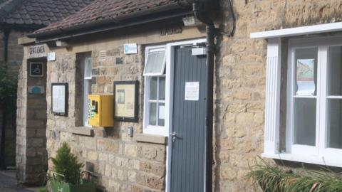 A stone building toilet block with signs for Gentlemen and Ladies