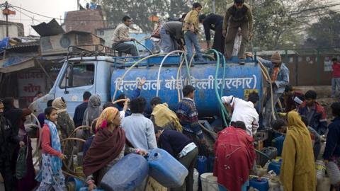 Indian residents of Govind Puri slum scramble with their siphon tubes over a New Delhi, India water board tanker during daily delivery of their fresh water supply February 7, 2008. In a city of 16 million, 25% of New Delhi residents have no access to piped water and 27% have piped water less than 3 hours per day. The World Bank reports India stood on the edge of an era of severe water scarcity. The city's population has grown over 40% in 15 years.