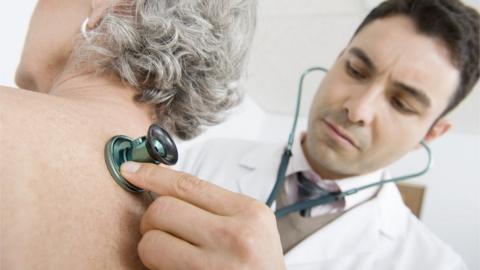 A GP listening to a woman's chest