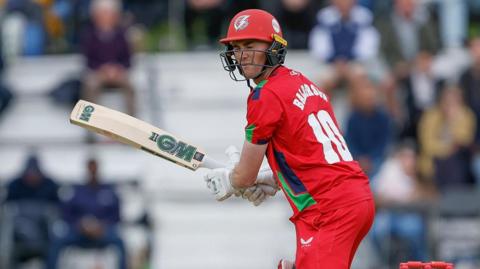 George Balderson batting for Lancashire in the T20 Blast. He has his bat held out and his eyes shut