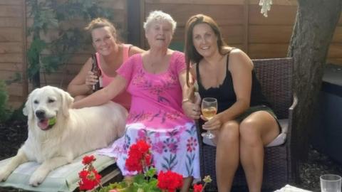 Paulette Crookes in the centre and her daughters either side of her. Denise Scott is on the right and there is also a dog resting beside them.