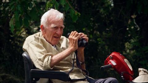 A man in a mobility scooter holding binoculars