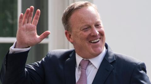 Outgoing White House Press Secretary Sean Spicer smiles as he walks into the West Wing