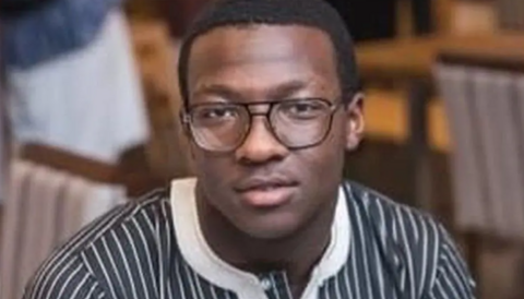 Alexander John Soyoye, 16, has short black hair, black framed glasses and is wearing a striped blue-and-white top.