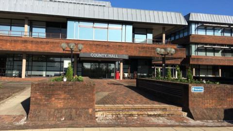 The main entrance to County Hall, Worcestershire County Council's current headquarters, with a set of brick steps leading to the door, in the foreground.