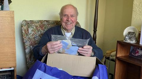 Alan pictured with a sack full of stamps in front of him