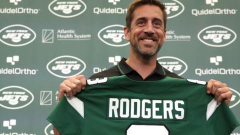 Aaron Rodgers holds up his New York Jets jersey