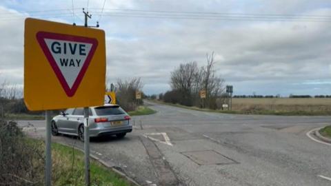 General image of the Wheatsheaf crossroads. There is a Give Way sign and a car waiting at the crossing