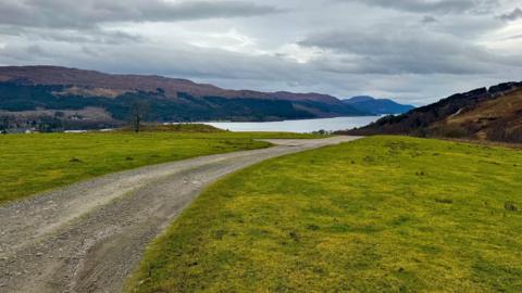 A view to Loch Ness from the Borlum Hill area. There is a rough track with neatly cropped grass on either side.