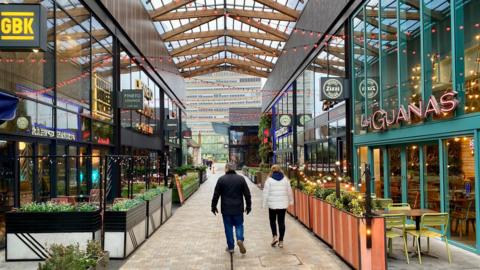 A general view of The Lexicon, with restaurants on either side with two people walking through the centre.